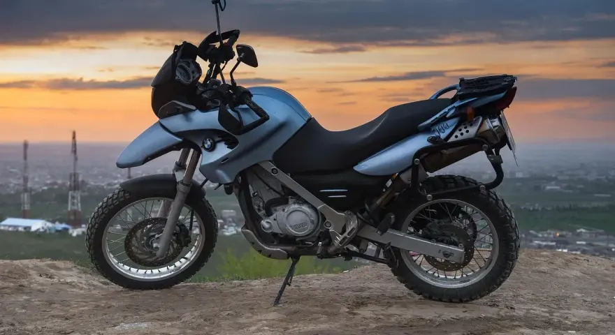 Niebieski motocykl BMW na wzgórzu, gotowy do podróży po Litwie, gdzie obowiązują ograniczenia prędkości.
