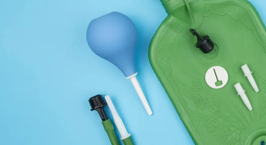 Grüne Spülflasche, blauer Birnensauger und Zubehör für die darmspiegelung vorbereitung auf blauem Hintergrund.