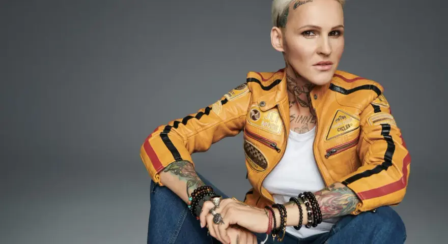 Agnieszka Chylińska w żółtej kurtce motocyklowej, z tatuażami i biżuterią. Jakby mówiła: "kiedyś do ciebie wrócę".