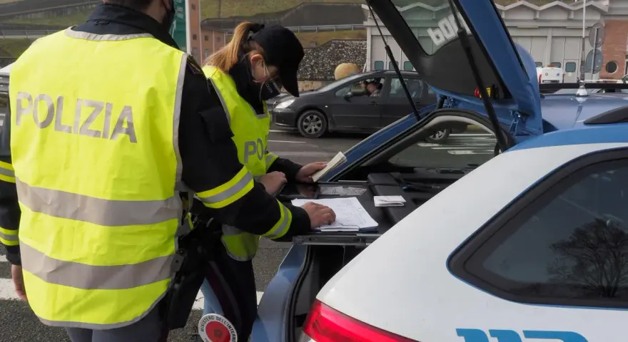 Agenti della Polizia Stradale controllano documenti, forse per un caso di targa clonata, durante un posto di blocco.