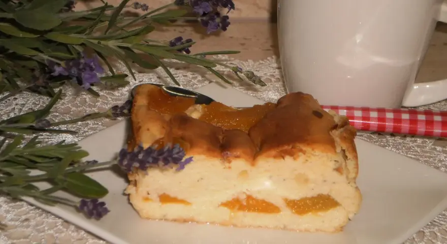 Pyszny sernik z brzoskwiniami, udekorowany gałązką lawendy, czeka na kawę.