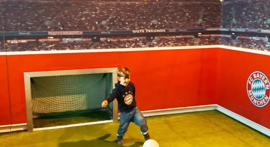 Kleiner Junge feiert seinen Allianz Arena Kindergeburtstag und kickt im FC Bayern Trikot.