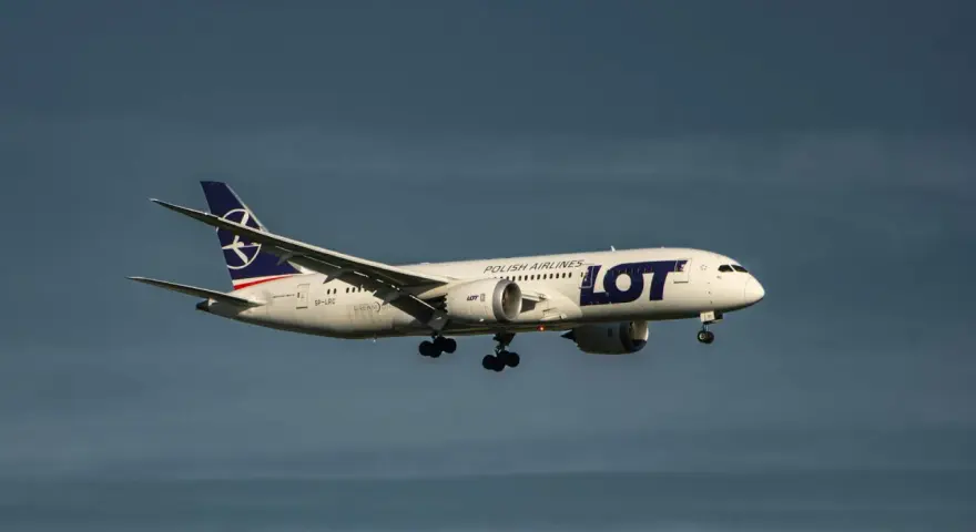 Samolot LOT Polish Airlines z bagażem podręcznym w locie, zbliżający się do lądowania.