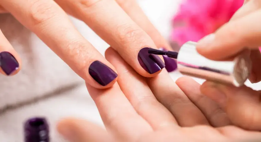 Applicazione smalto viola su unghie. Scopri come usare la fibra di vetro per unghie per un look impeccabile.