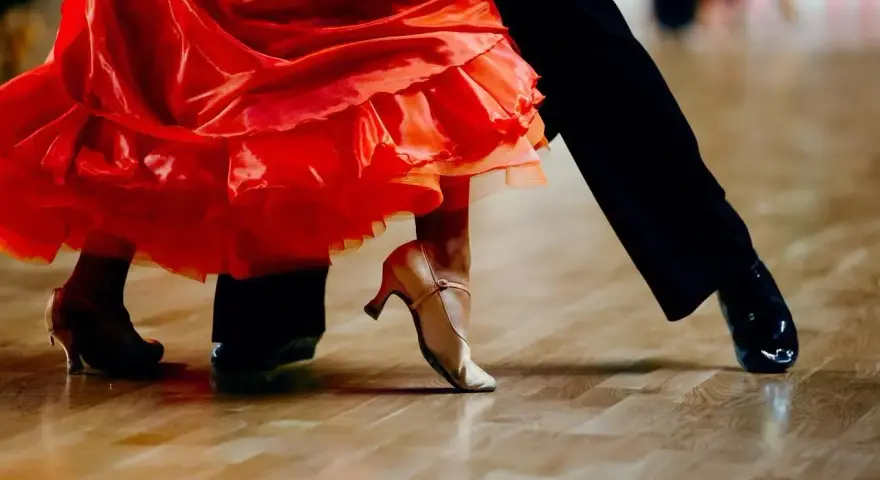Para tańczy paso doble w rytm muzyki. Czerwona sukienka wiruje, a eleganckie buty poruszają się po parkiecie.