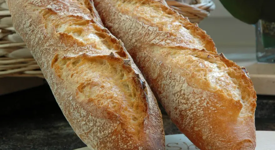 Zwei knusprige Baguettes, eine köstliche t65 Mehl Alternative, liegen auf einem Holzbrett.