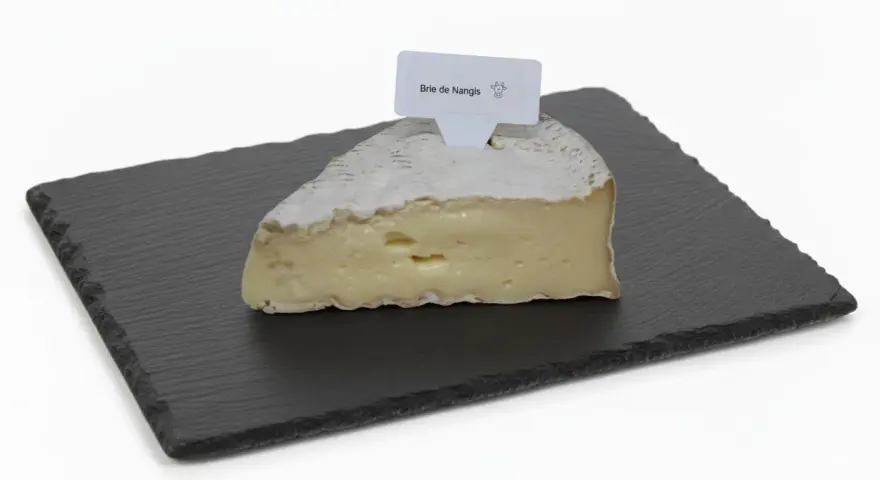 Une part de brie de Nangis, crémeux et à la croûte fleurie, repose sur une ardoise.