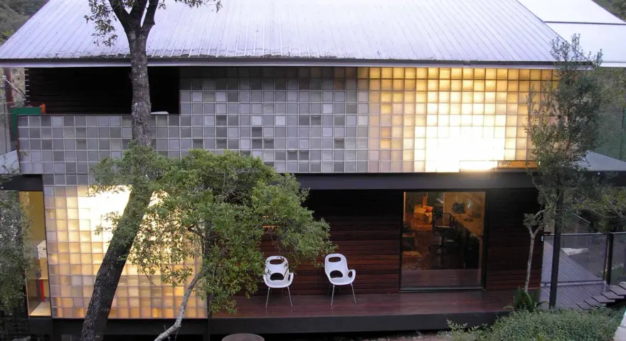 Modern house with a striking glass block installation, bathing the interior in warm light.