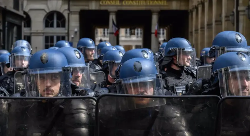 Un grupo de gendarmes con cascos azules y escudos protectores se prepara para mantener el orden frente al Conseil Constitutionnel.