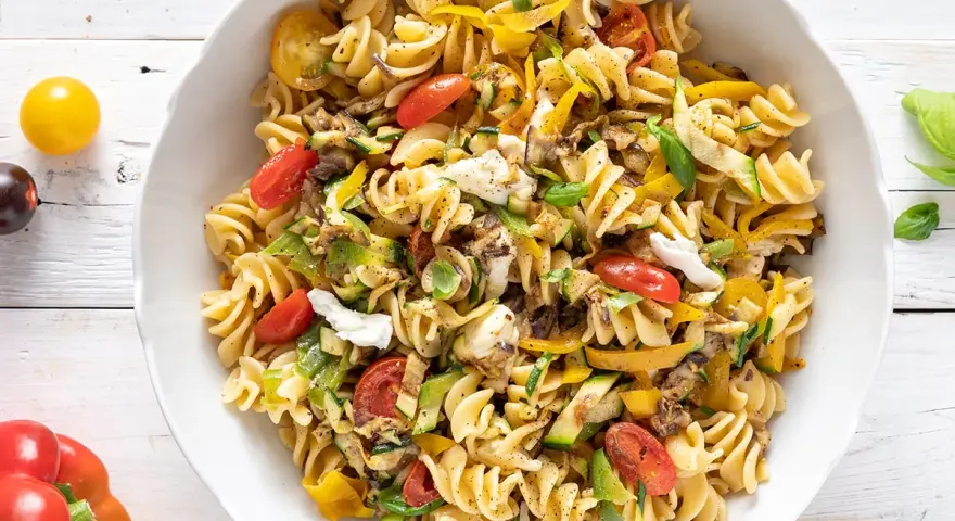 Un piatto colorato di pasta estiva veloce con fusilli, zucchine, peperoni gialli, pomodorini e mozzarella.