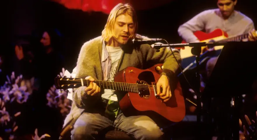 Kurt Cobain gra na gitarze akustycznej, czuć atmosferę, która pachnie nirvaną.