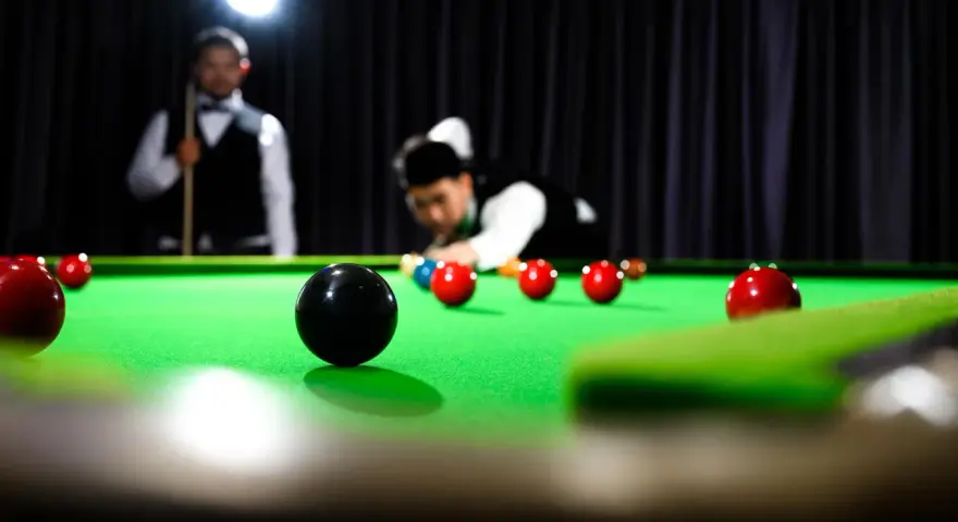 Gracze w skupieniu rozgrywają mecz snookera, zbliżając się do zwycięstwa w snooker mistrzostwa świata.
