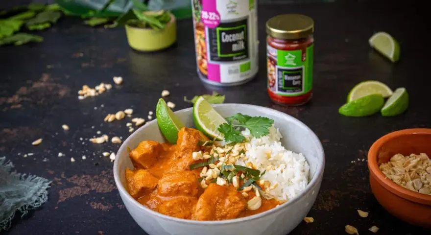 Aksamitny kurczak w sosie massaman curry, podany z ryżem, limonką i posypany orzeszkami. Obok puszka mleka kokosowego i słoiczek pasty massaman.
