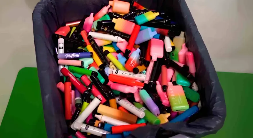 Contenedor lleno de vapes desechables de colores. ¿Qué hacer con un vape desechable? Reciclaje responsable.