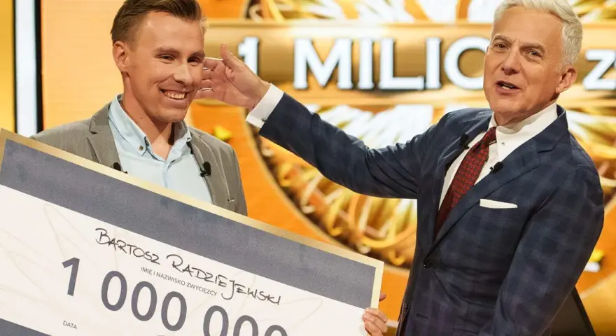 Bartosz Radziejewski, który wygrał milion w Milionerach, odbiera czek z nagrodą od Huberta Urbańskiego.