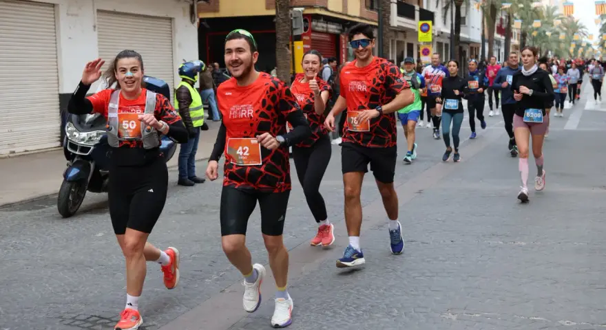 Corredores alegres participan en una media maratón, con dorsales visibles. El ambiente festivo sugiere un evento deportivo emocionante, parte de un calendario de medias maratones.