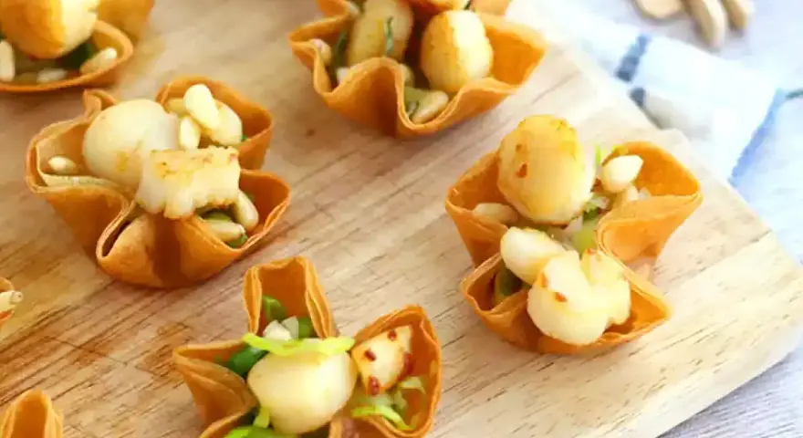 Bouchées à la reine aux Saint-Jacques, garnies d'une béchamel crémeuse et de pignons. Un délice croustillant.