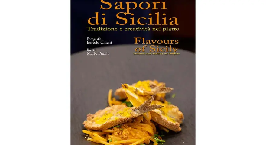 Un piatto di spaghetti con pesce fritto e scorza d'arancia, che celebra i sapori tipici siciliani.