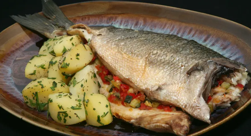Lubina al horno con verduras y patatas. Un plato principal delicioso y saludable.