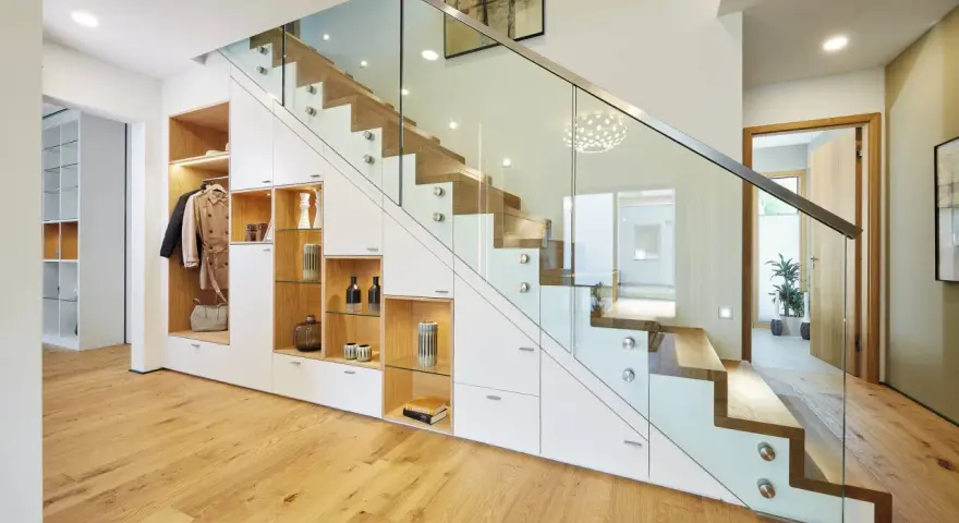 Schickes **schmales Reihenhaus einrichten**: Stauraumwunder unter der Treppe mit Garderobe, Regalen und Schubladen. Moderne Glasbrüstung.
