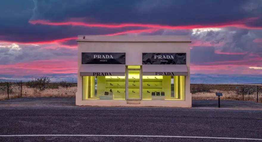 Prada Marfa, une installation artistique isolée au Texas, se dresse sous un ciel crépusculaire aux teintes roses et violettes.