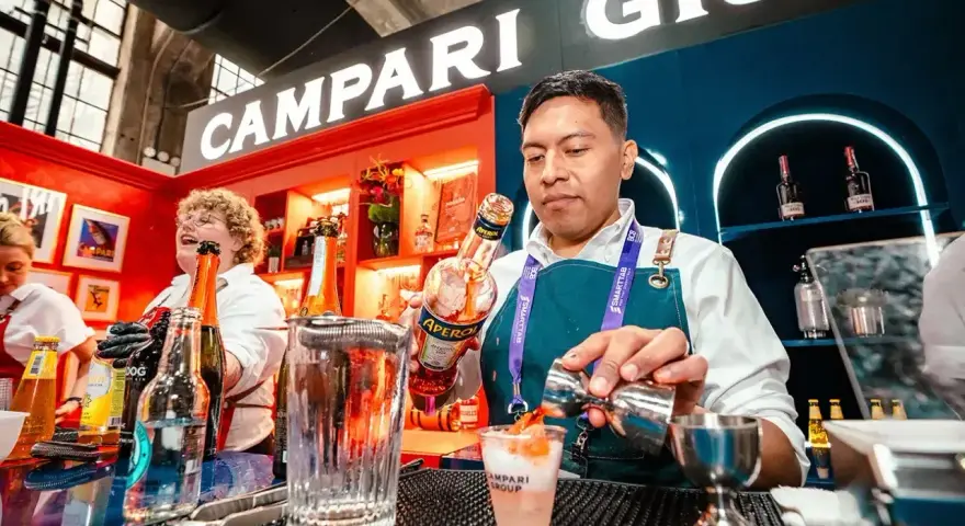 Barman nalewa Aperol do drinka, w tle logo Campari.