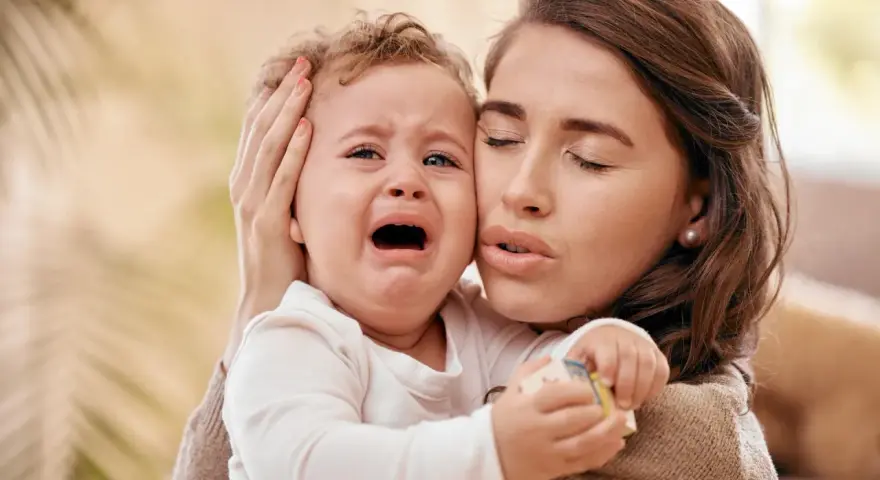 Zmartwiona mama tuli płaczące dziecko. Czy to mamoza?