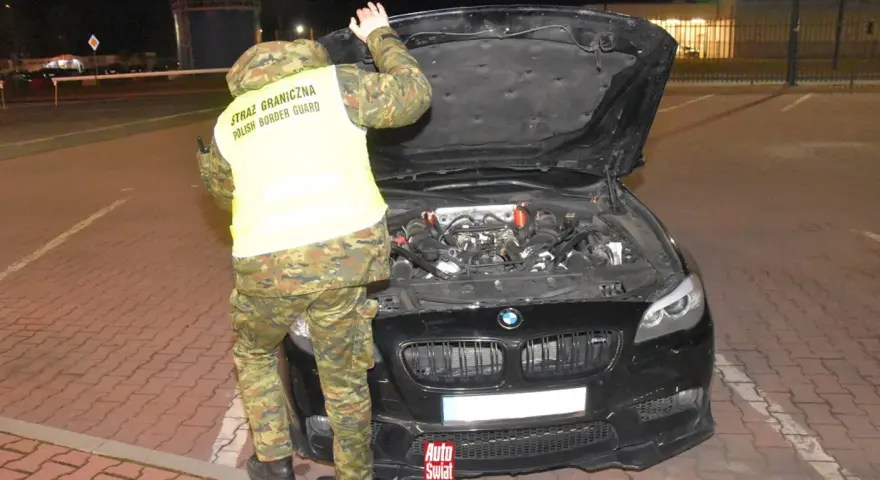 Funkcjonariusz Straży Granicznej sprawdza silnik BMW, wykonując rozkodowanie VIN.