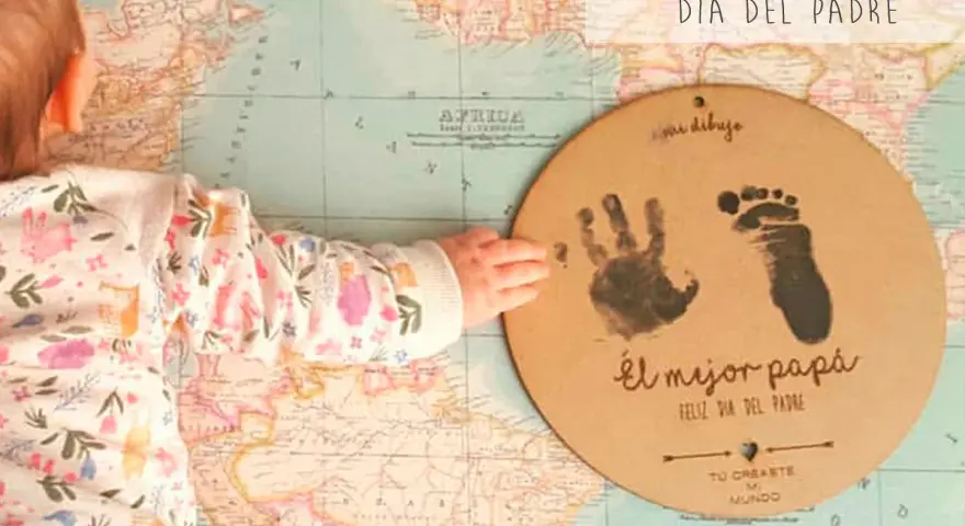 Manualidad Día del Padre 2 años: huella de mano y pie de bebé en un círculo de cartón sobre un mapa.