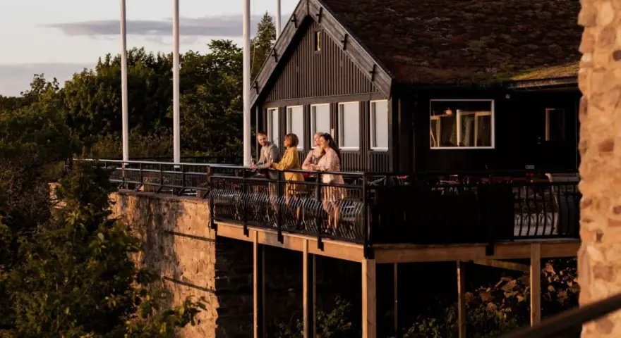 Vänner njuter av kvällssolen på balkongen vid Gyllene Utterns rastplats.