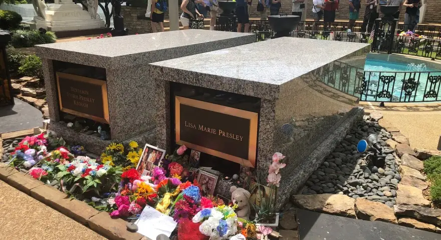 Gräber von Lisa Marie und Benjamin Keough, umgeben von Blumen. Viele Besucher ehren das Erbe von Elvis Presley.