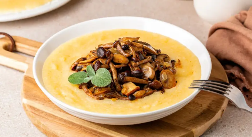 Polenta cremosa con champiñones salteados y una ramita de salvia. Un plato reconfortante que te hará preguntar: ¿polenta que es? ¡Deliciosa!