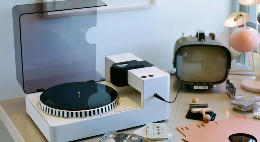 Moderner Plattenspieler mit Vinyl-Schallplatte, Kassetten und Retro-Fernseher. Hier wird die Frage "was ist Vinyl Musik" visuell beantwortet.