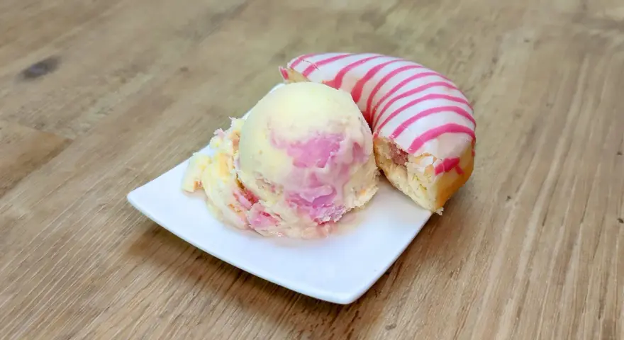 Ein cremiges Eis mit rosa Schlieren neben einem Donut mit rosa Streifen. Perfekt für eine süße Auszeit!