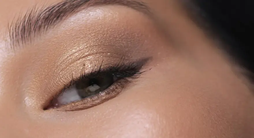 Maquillage paupière tombante : ombre dorée scintillante, trait d'eye-liner fin et cils longs pour un regard sublimé.