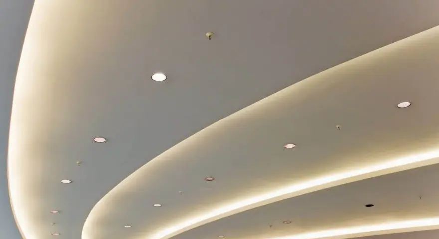 Nowoczesny podwieszany sufit z ukrytym oświetleniem LED tworzy łagodne, faliste linie, dodając przestrzeni elegancji.