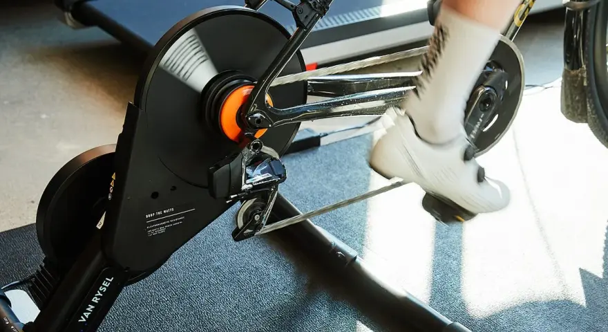 A cyclist's feet pedal on a bike connected to a magnetic resistance trainer, ready for an indoor workout.