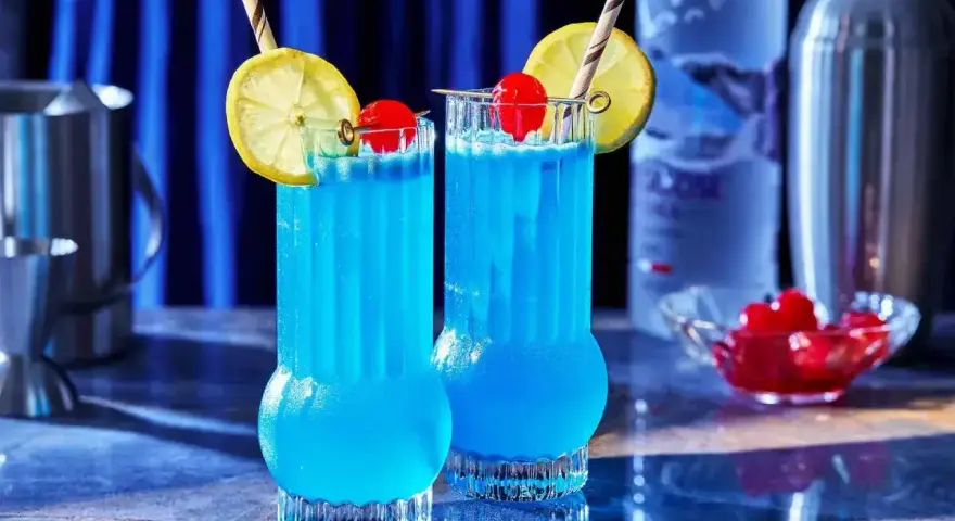 Dwa błękitne drinki Kamikaze, ozdobione cytryną i wiśnią, idealne do picia w letni wieczór.