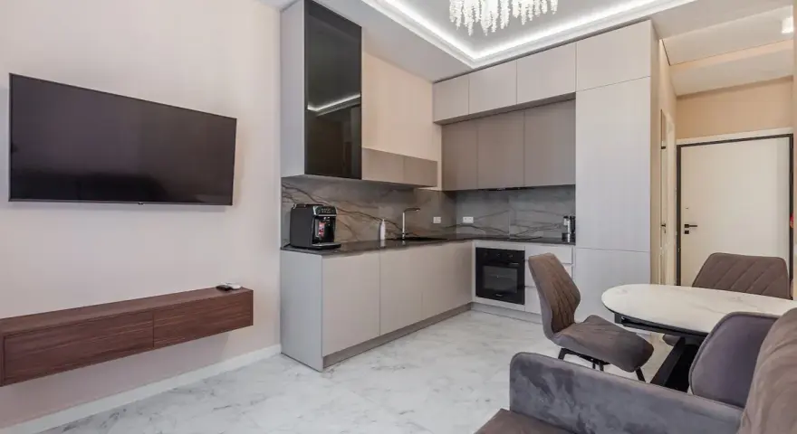 Un moderno open space lungo e stretto con cucina a vista, zona TV e tavolo da pranzo.