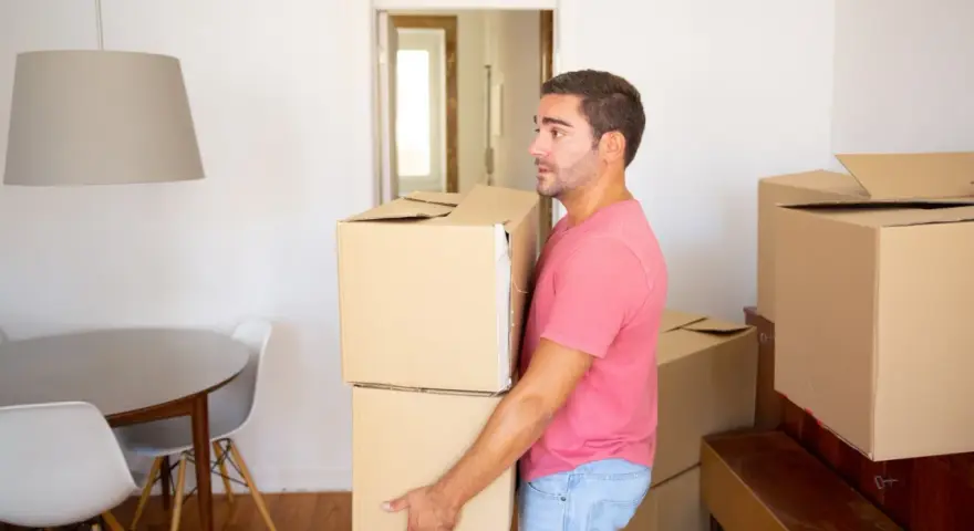 Un homme porte des cartons, prêt à quitter le domicile conjugal. Le propriétaire semble pensif, entouré de cartons de déménagement.