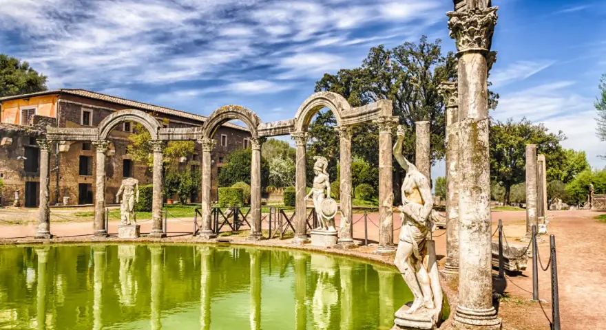 Starożytne ruiny i rzeźby w Villa d'Este odbijają się w zielonym stawie.