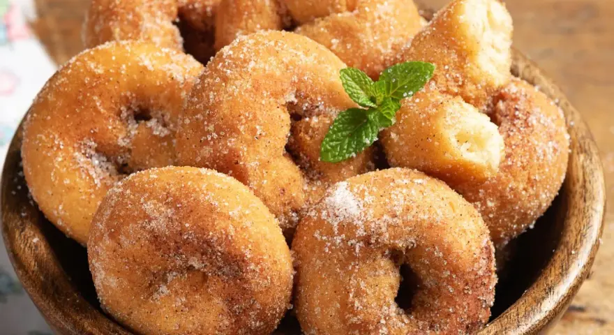 Rosquillas de la abuela esponjosas, cubiertas de azúcar y canela, con una ramita de menta. ¡Un placer casero!
