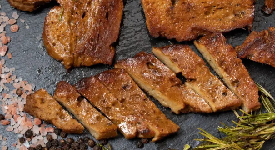 Pokrojony seitan, przypominający mięso, z rozmarynem i solą. To świetna alternatywa dla mięsa, jeśli zastanawiasz się, seitan co to.