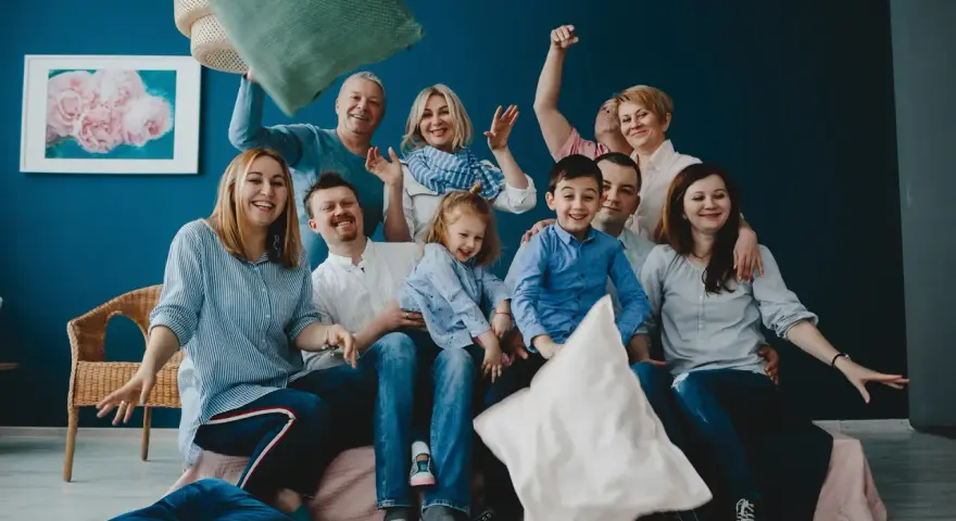 Wesoła rodzina patchworkowa rzuca poduszkami, śmiejąc się i ciesząc wspólnym czasem.