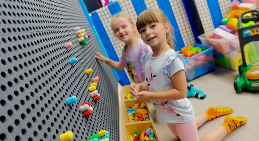 Dwie dziewczynki bawią się w sali zabaw. Idealny strój na urodziny do sali zabaw to wygodne ubranie i kolorowe skarpetki.