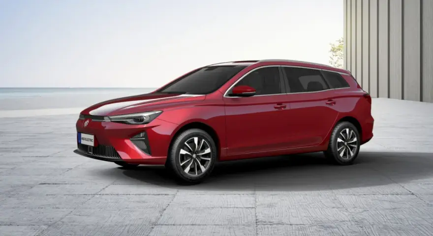 Czerwony MG5 Electric, kombi, stoi na betonowym placu z widokiem na morze.