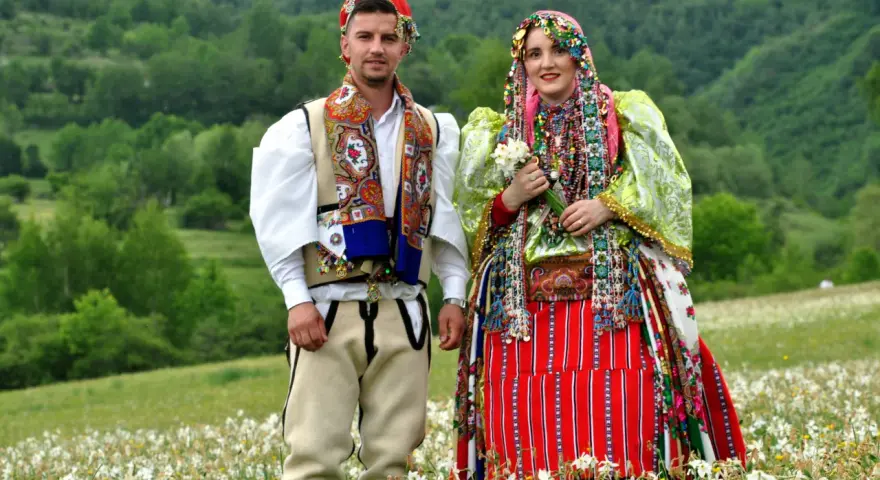 Para w tradycyjnych strojach na tle zielonych wzgórz. Ciekawe albania ciekawostki o kulturze i tradycji.