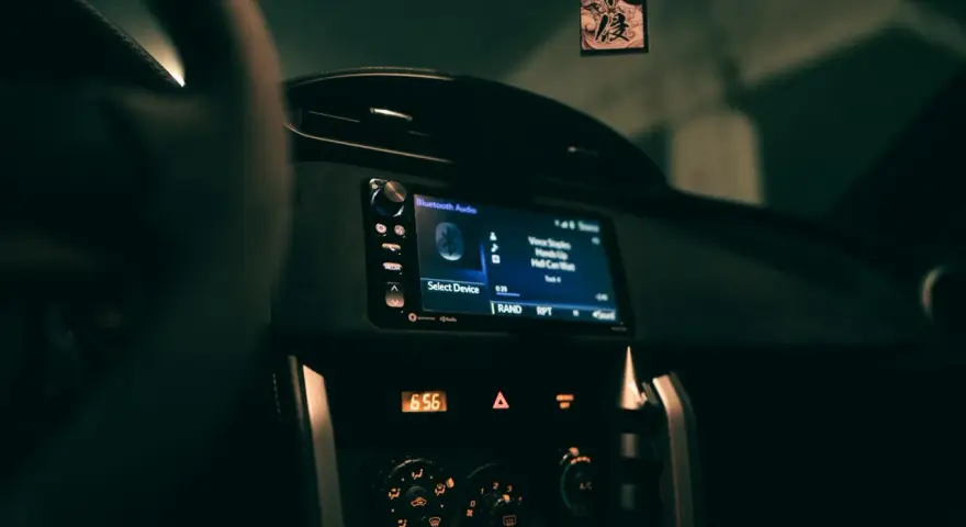 Wnętrze samochodu z włączonym radiem, na ekranie wyświetla się "Bluetooth Audio" i tytuł piosenki. Zastanawiasz się, co to jest treble w kontekście dźwięku? To wysokie tony.