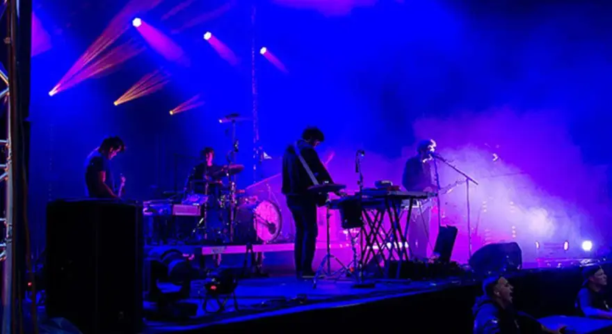 Un groupe allemand des années 2010 joue sur scène sous des lumières bleues et violettes.