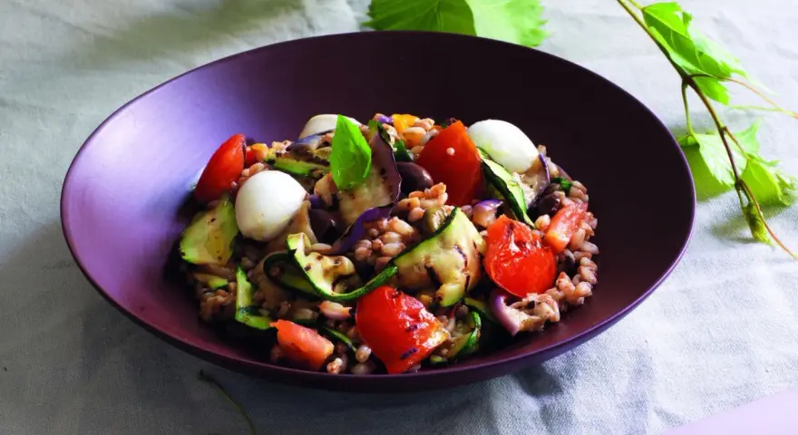 Insalata di farro estiva con verdure grigliate, pomodorini, mozzarelline e basilico fresco.